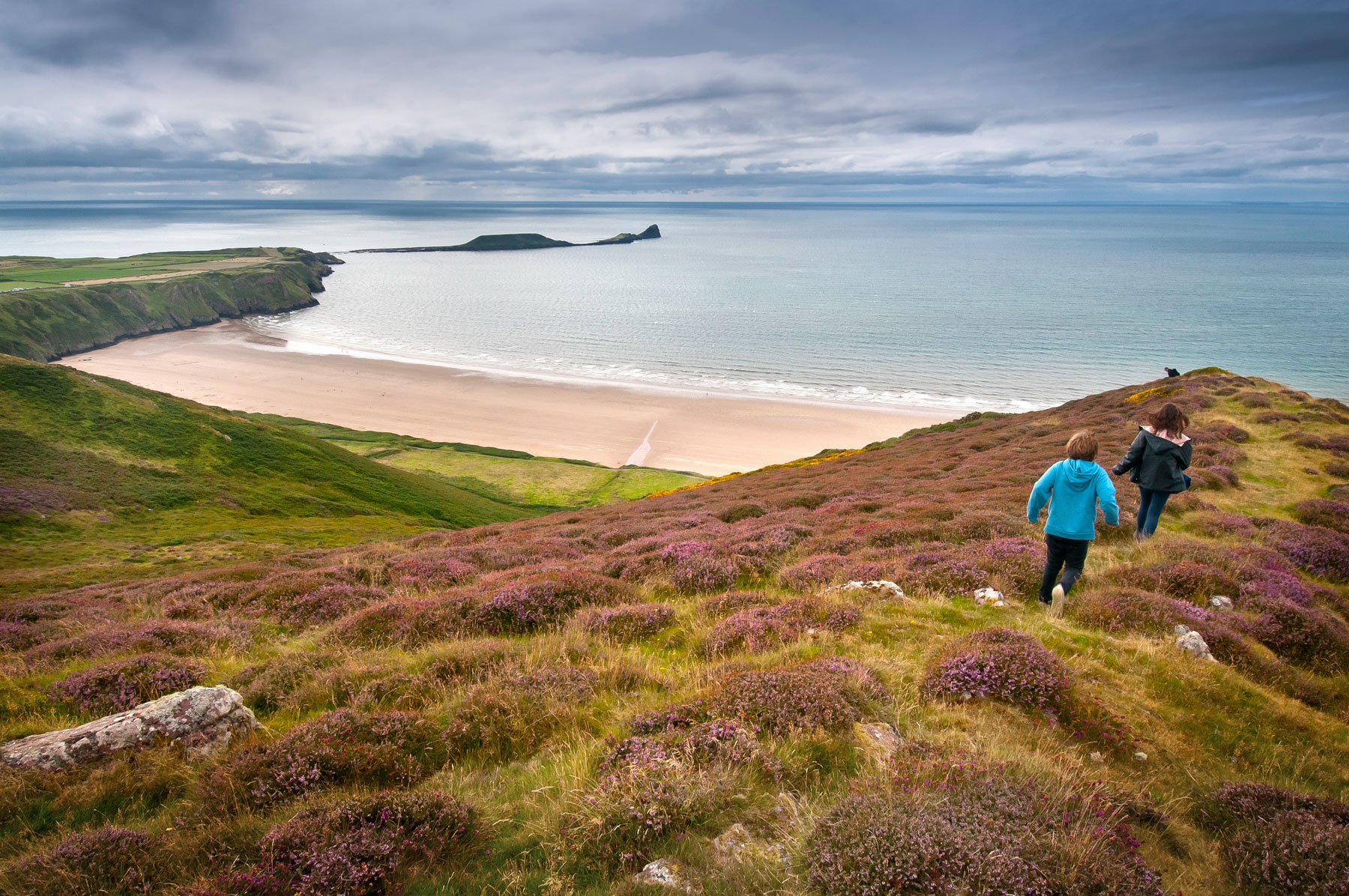 Blick auf die malerische Rhossili Bay auf der Halbinsel Gower und die Gezeiteninsel Worm's Head © Crown Copyright (2022) Visit Wales